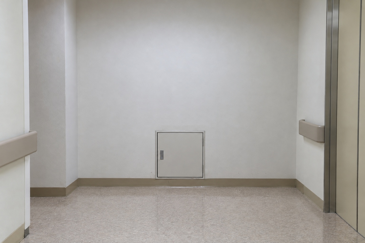 職員が朝に撮影し、病院管理者から提供された写真。東廊下の突き当たりの白い壁に、床に近い四角い点検蓋がある。人が立って通る高さの扉は写っていない。