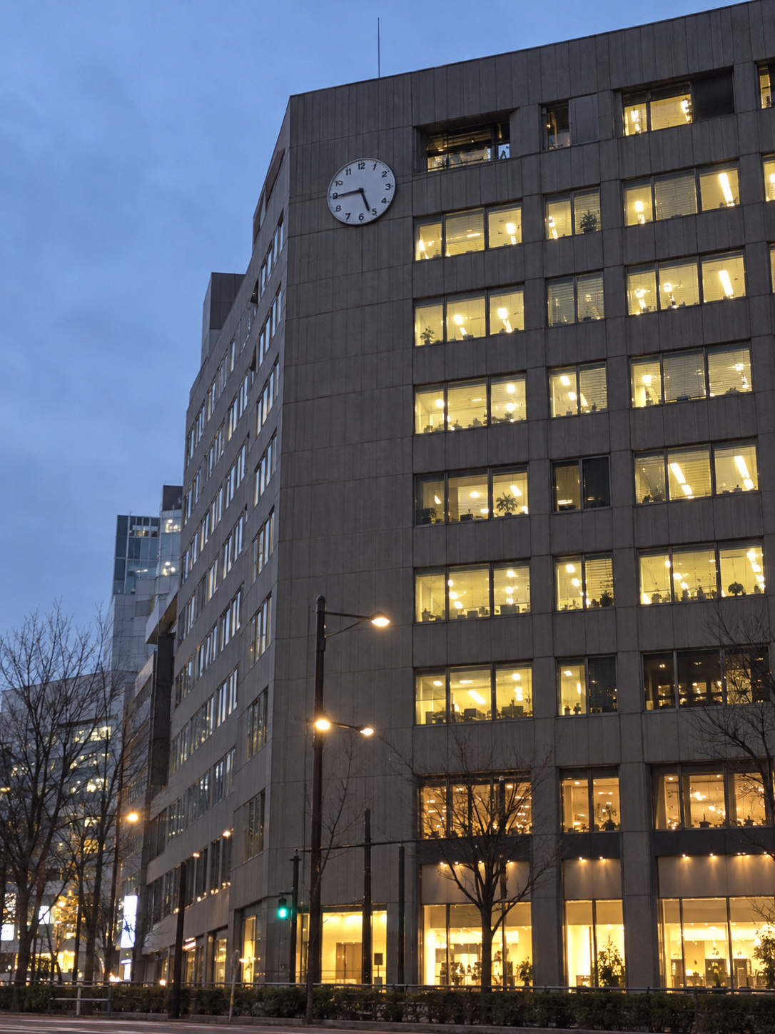 情報提供者撮影。夕方のビルを見上げた縦長の写真。壁の上部に数字のある丸い時計が1つ写り、窓には明かりがついている。向かいの駅と駅の時計は画面に入っていない。