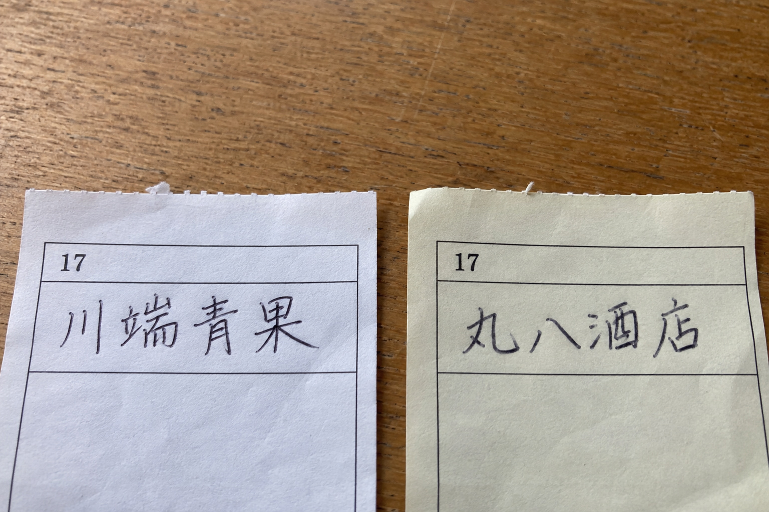 霧島秀一撮影。番号17の受領証2枚の店名欄。左の白い紙には「川端青果」、右の控えには「丸八酒店」と書かれている。