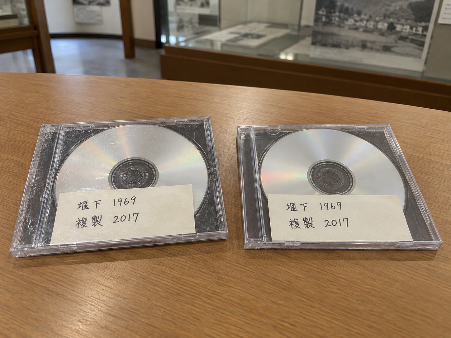 霧島秀一撮影。透明なケースに入った銀色のディスク2枚。どちらの紙ラベルにも「堰下 1969」「複製 2017」と書かれている。