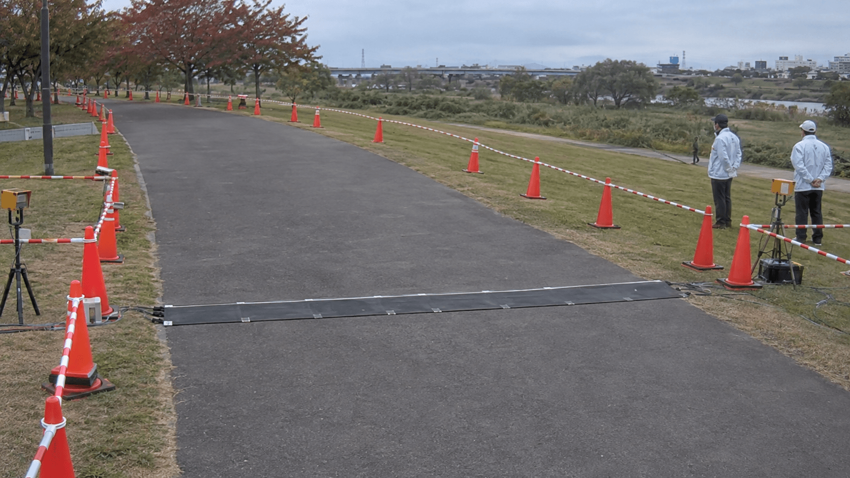 大会事務局の定点映像から切り出した画像。黒い計測用マットの上と前後に走者は見えず、コース脇で係員が待っている。