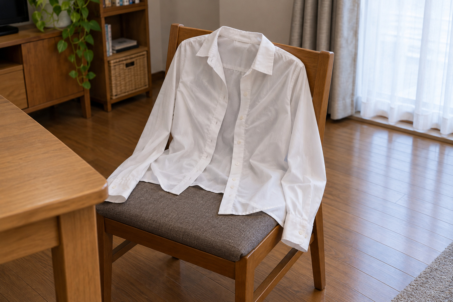 霧島秀一撮影。木の椅子へ広げられた白い長袖の前開きブラウス。前のボタンは留められておらず、胸の布に斜めのしわがある。